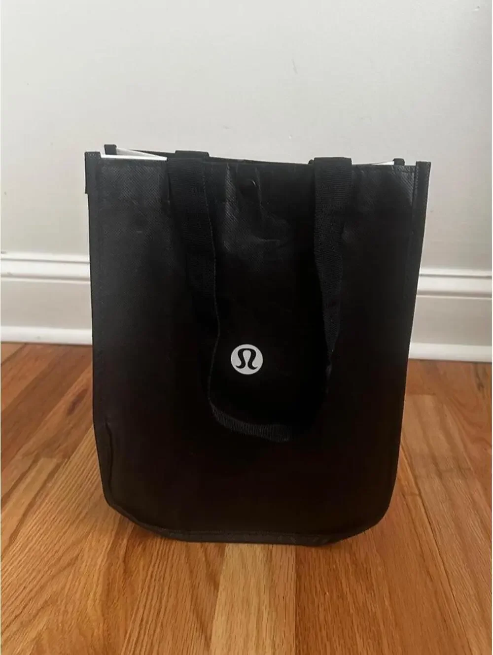 Black Lululemon tote bag with white vertical text reading